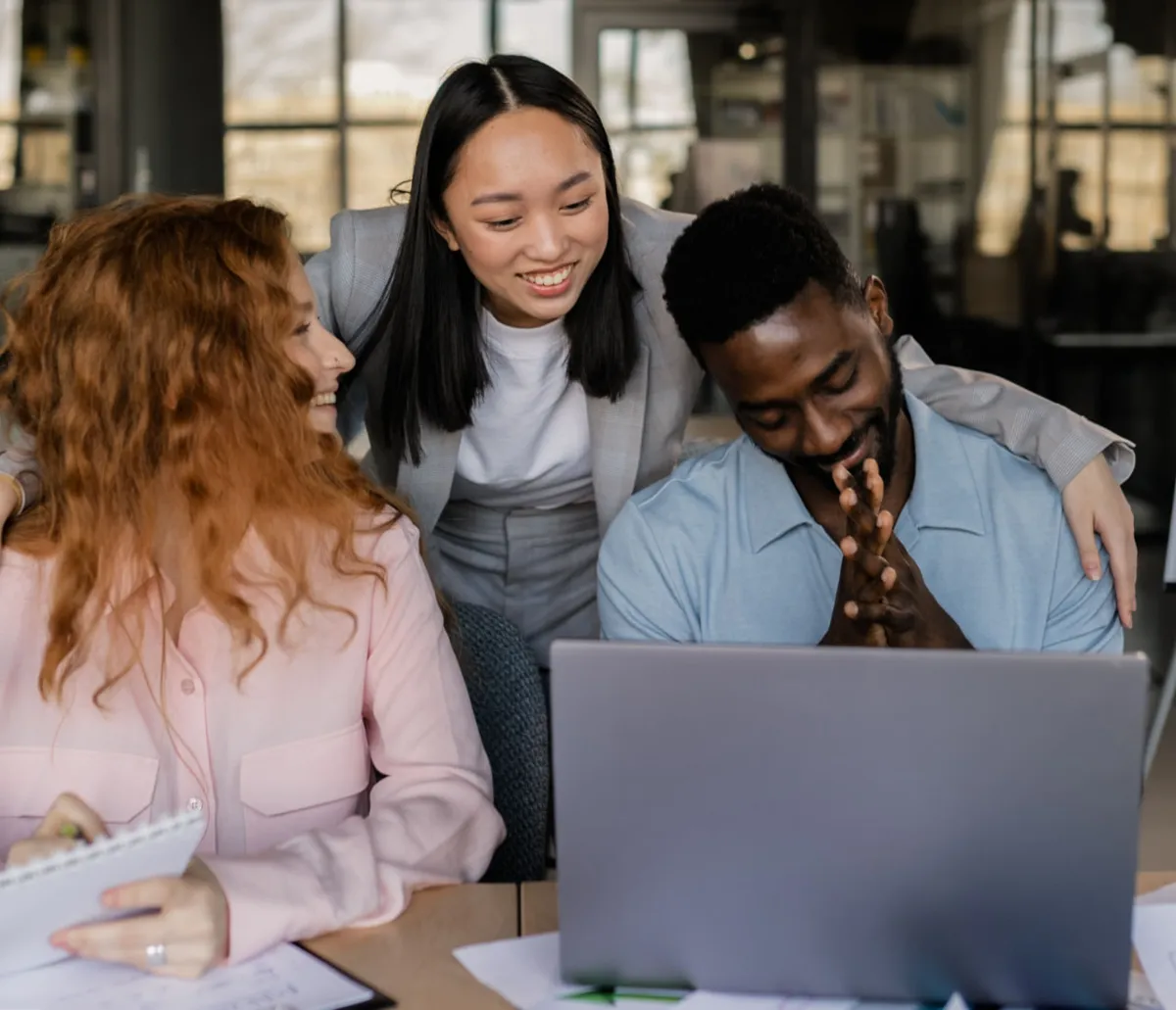 Three marketing professionals collaborating around a laptop
